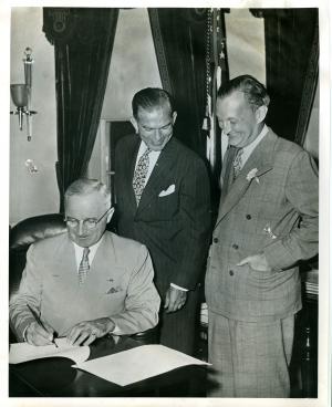 President Truman signs the Fulbright Act Aug 1, 1946, #015, as Senator Fulbright, center, and Assistant Secretary of State for Public Affairs, Benton, beam.